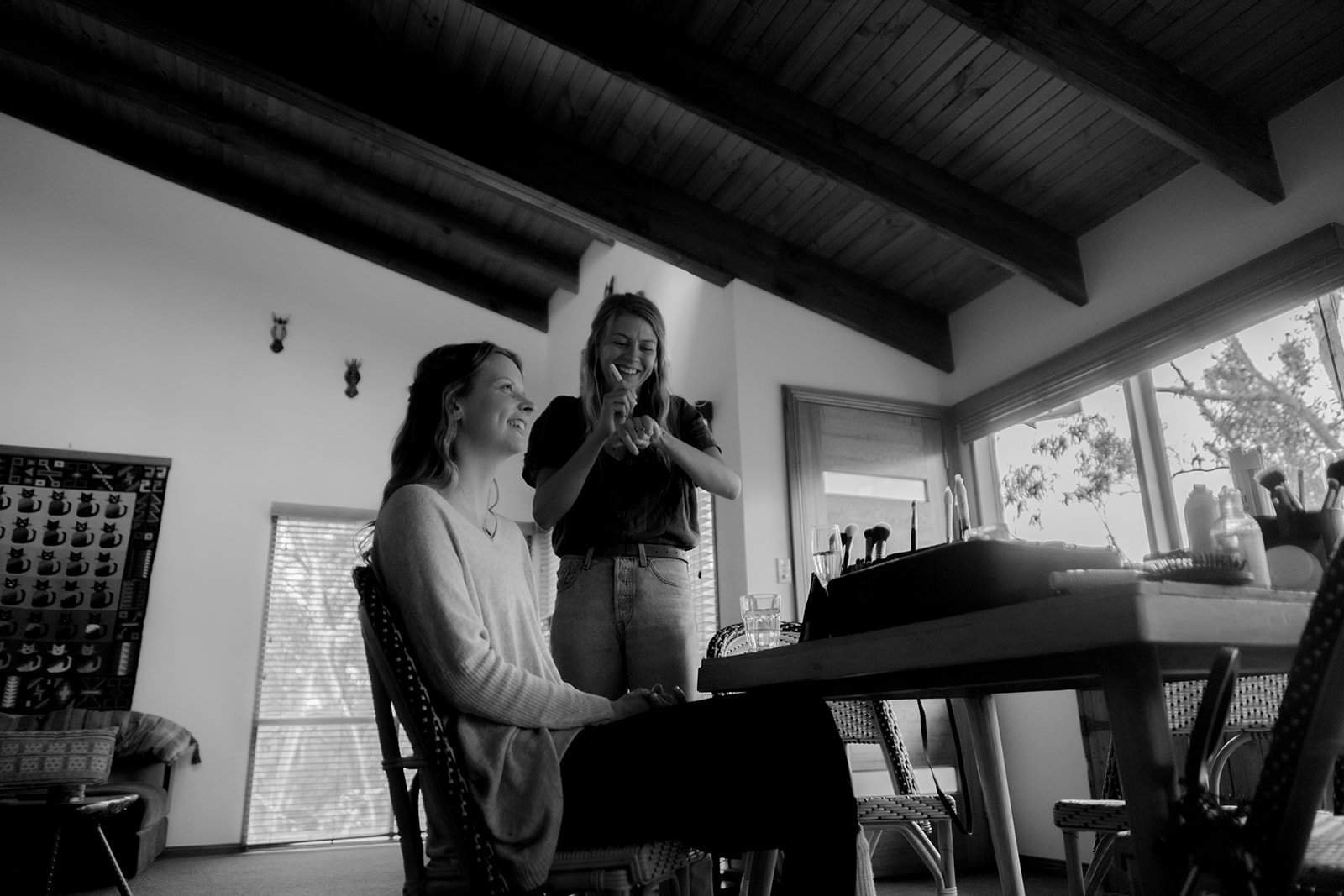 Makeup artist applying natural makeup to a client in a bright, airy room